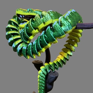 May include: A green and yellow snake figurine coiled around a branch. The snake has a textured surface and a realistic appearance.