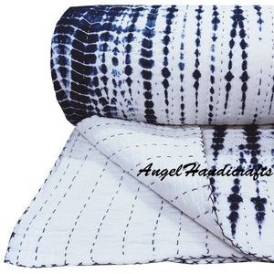 May include: A white and navy blue tie-dye patterned quilt. The quilt features a repeating vertical design with dark blue splotches and lines against a white background. The quilt is folded over, showing the stitching and the text "Angel Handicrafts".