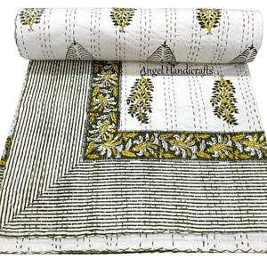 Op de afbeelding: Witte en groene Kantha-quilt met een bloemen- en streepmotief. De quilt heeft een opgerold gedeelte aan de bovenkant, dat het ontwerp laat zien. De rand heeft een gedetailleerd bloemmotief in groen en geel. De tekst "Angel Handicrafts" is zichtbaar.