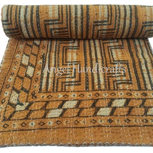 May include: A rolled-up, patterned textile with a geometric design in shades of brown, beige, and black. The textile features a repeating pattern of lines and shapes, with visible stitching. The text "Angel Handicrafts" is visible.