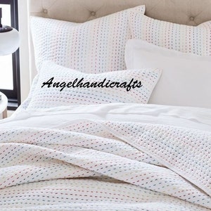 May include: White cotton quilt with colorful stitching in a random pattern. The quilt is on a bed with white pillowcases and a white pillow with the text "Angelhandicrafts" in black.