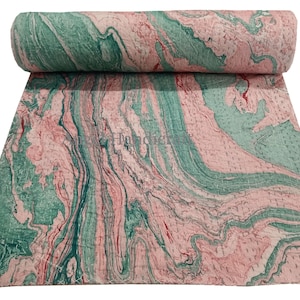 Op de afbeelding: Een opgerolde quilt met een marmerpatroon in roze en blauwgroen. De quilt is uitgespreid en toont een wervelend ontwerp. De stof heeft een zachte, getextureerde uitstraling, met zichtbare stiksels. Dit textiel is geschikt voor beddengoed of woondecoratie.