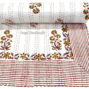 Peut inclure: Couverture blanche à motifs floraux bruns et jaunes, avec une section enroulée. La couverture présente un motif floral répété et une bordure rayée. Le texte "Angel Handicrafts" est visible sur la couverture.