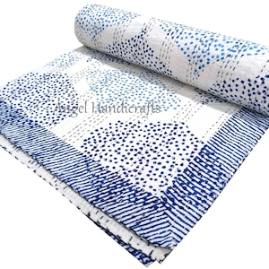Op de afbeelding: Een wit en blauw patroon quilt met een opgerold gedeelte. De quilt heeft een ontwerp van blauwe stippen en lijnen op een witte achtergrond. De rand heeft een gestreept patroon. De tekst "Angel Handicrafts" is zichtbaar.