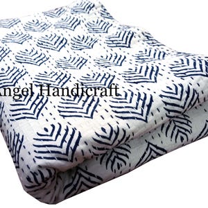 Op de afbeelding: Witte kantha-deken met een blauw geometrisch patroon. De deken is dubbelgevouwen en heeft een label met de tekst "Angel Handicraft".