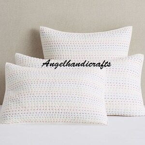 May include: Two white quilted pillow covers with a subtle striped pattern in shades of pink, blue, and white. The pillow covers are made of cotton and have a soft, comfortable feel.