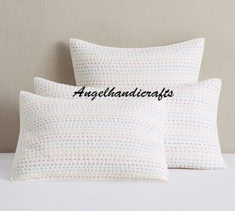 May include: Two white quilted pillow covers with a subtle striped pattern in shades of pink, blue, and white. The pillow covers are made of cotton and have a soft, comfortable feel.