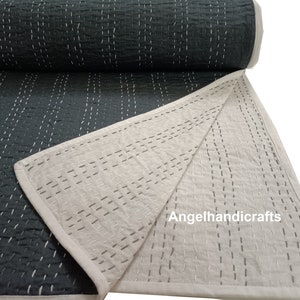 May include: A dark gray kantha quilt with white stitching. The quilt is folded in half, revealing a white underside with the same stitching pattern. The text "Angelhandicrafts" is visible on the white side.