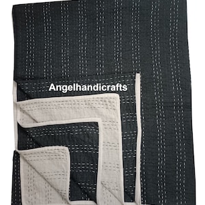 May include: A black and white kantha quilt with a white border. The quilt is folded in half and the white side is visible. The quilt is hand-stitched and has a traditional design. The text "Angelhandicrafts" is visible on the quilt.