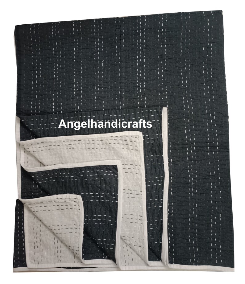 May include: A black and white kantha quilt with a white border. The quilt is folded in half and the white side is visible. The quilt is hand-stitched and has a traditional design. The text "Angelhandicrafts" is visible on the quilt.