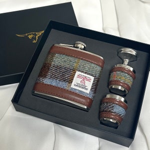 Pode incluir: Um conjunto de tr&ecirc;s frascos de prata com um padr&atilde;o de tweed marrom e azul. Os frascos est&atilde;o em uma caixa preta com as palavras "Harris Tweed" impressas no frasco maior.
