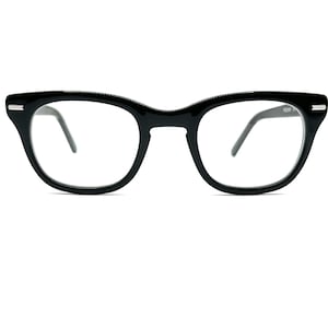 May include: Black eyeglasses with a thick, rounded frame. The glasses have clear lenses and thin temples. The frame has a slight cat-eye shape. The glasses are set against a white background.