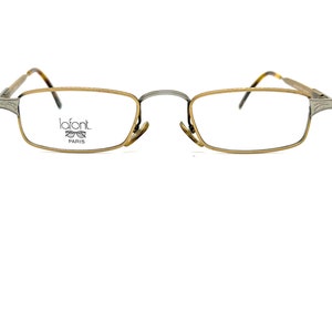 May include: Gold-toned Lafont eyeglasses with rectangular lenses. The frames have a thin, metallic design with a bridge connecting the two lenses. The temples are a darker color, and the Lafont logo is visible on the left lens.