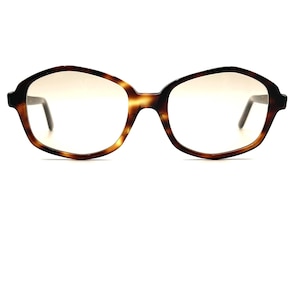 May include: Tortoiseshell-patterned eyeglasses with a geometric frame. The lenses have a gradient tint, transitioning from a light color at the top to clear at the bottom. The temples are dark and slender, and the glasses are set against a white background.