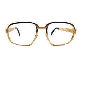 May include: Gold-toned metal eyeglasses featuring a rectangular frame shape with rounded corners. The bridge and temples have a textured finish, while the temple tips are black. The lenses are clear and transparent, set within the metallic frame.