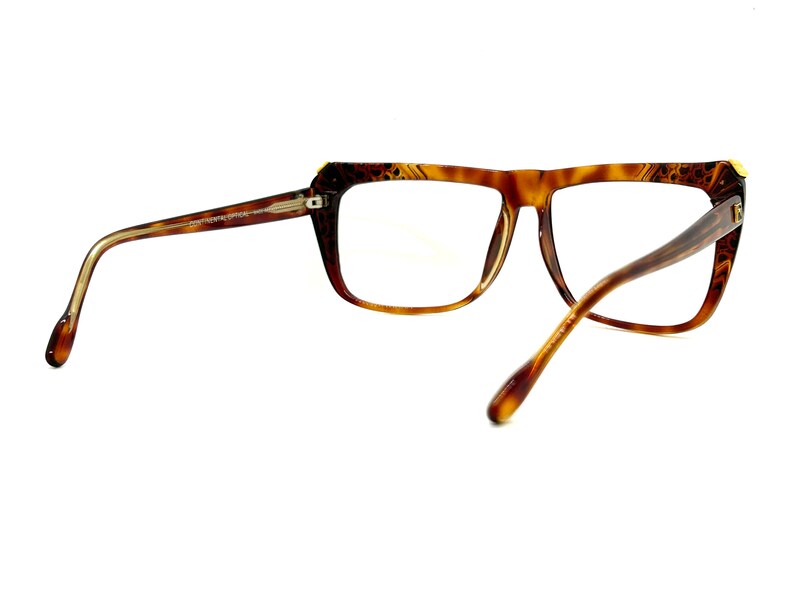 May include: Brown tortoise shell eyeglasses with gold accents. The glasses have a rectangular frame with a slight cat-eye shape.