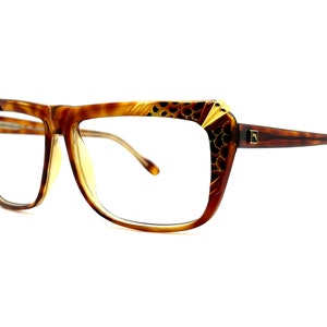 May include: Brown tortoise shell eyeglasses with gold accents and a leopard print design on the frame.