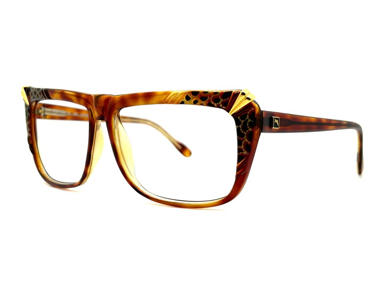 May include: Brown tortoise shell eyeglasses with gold accents and a leopard print design on the frame.