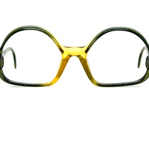 May include: A pair of eyeglasses with a dark green frame and gold accents. The lenses are clear.