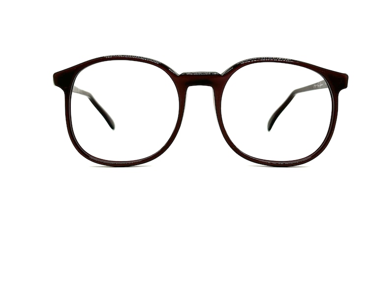 May include: A pair of brown round spectacles with clear lenses.