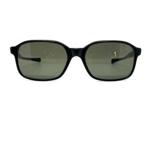 May include: Black sunglasses with a rounded rectangular frame and grey lenses. The sunglasses have a classic design, suitable for everyday wear. The frame is made of a glossy material.