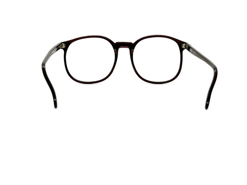 May include: A pair of round, dark brown spectacles with black arms.