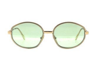 May include: A pair of oval-shaped sunglasses with a gold metal frame and green lenses.