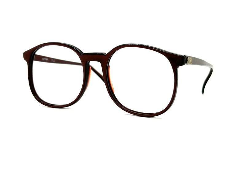 May include: Brown plastic framed spectacles with round lenses. The frames have a subtle tortoiseshell pattern.