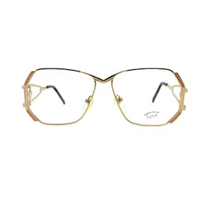 May include: Gold-tone metal eyeglasses with a geometric frame and clear lenses. The lenses are labeled "Demonstration Lens".