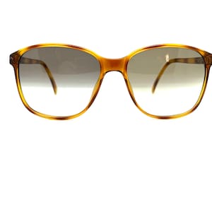 May include: A pair of tortoise shell sunglasses with brown gradient lenses.