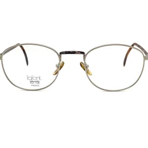 May include: Silver-toned metal eyeglasses with round frames and clear lenses. The brand name "lafont. PARIS" is printed on the left lens.