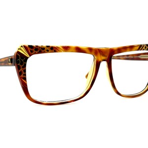 May include: Brown tortoise shell eyeglasses with gold accents on the frame. The glasses have a square shape with a slight cat-eye design.