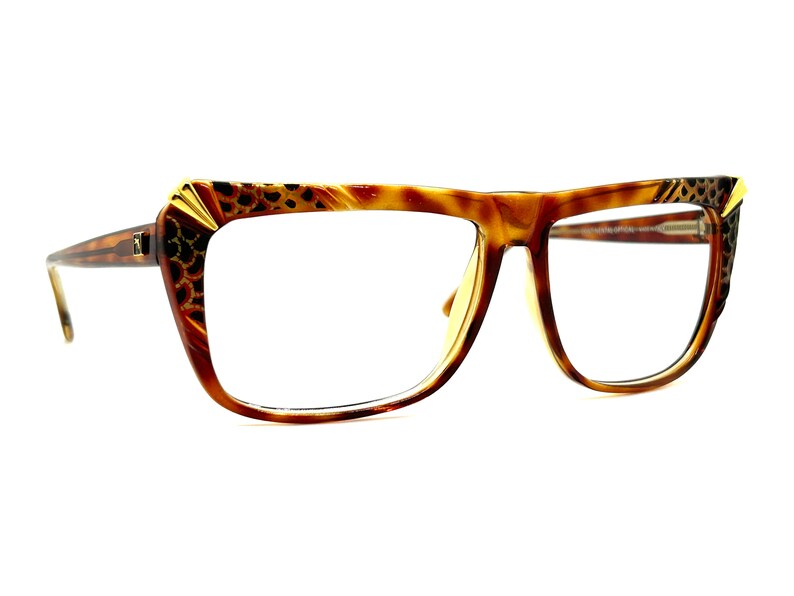May include: Brown tortoise shell eyeglasses with gold accents on the frame. The glasses have a square shape with a slight cat-eye design.