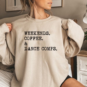 Może przedstawiać: Beżowa bluza z nadrukiem "Weekends. Coffee. & Dance Comps." w kolorze czarnym.