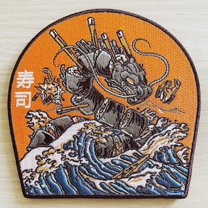 Peut inclure: Un patch brodé représentant un dragon noir émergeant d'une vague bleue avec un caractère japonais "青" en blanc sur un fond orange.