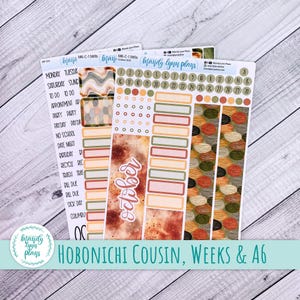 May include: Three sheets of adhesive planner stickers featuring the text Mandy Lynn Plans. The sheets include date circles numbered 1 through 31, rectangular labels in muted earth tones, decorative strips with abstract patterns, and text labels.