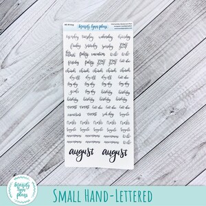 May include: A sheet of small, hand-lettered planner stickers with black text. The stickers include words like "Tuesday," "Party," and "Birthday." The word "August" is written in a cursive font at the bottom. The stickers are on a white background.