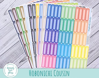 May include: A set of 18 colorful sticker sheets with rectangular labels, each with a hole at the top. The labels are arranged in a rainbow pattern. The sticker sheets are labeled "HOBONICHI COUSIN" and "Mandy Lynn Plays".
