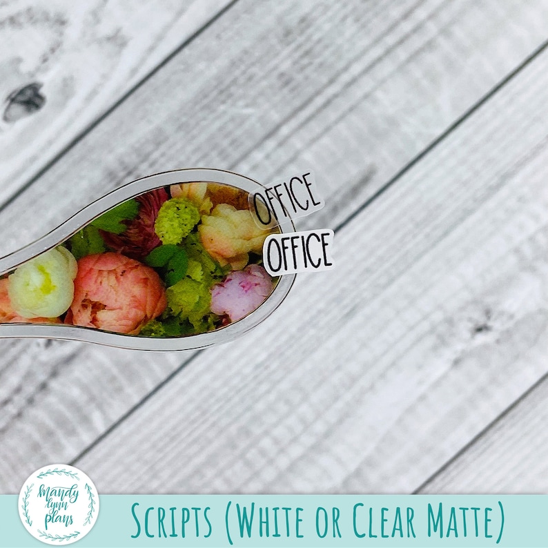 May include: A clear, teardrop-shaped sticker with the word "OFFICE" in black, placed over a floral arrangement of pink, yellow, and green flowers. The sticker is part of a set labeled "SCRIPTS (WHITE OR CLEAR MATTE)".