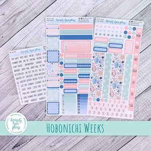 May include: A collection of pastel-coloured planner stickers, with pink, blue, and peach hues. The stickers include floral designs, boxes, and labels for weekly and daily planning. The text "Hobonichi Weeks" is visible.