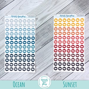 May include: Two sheets of stickers featuring an open book design. The stickers are in two colour schemes: ocean and sunset. The ocean stickers are shades of blue, teal, and grey. The sunset stickers are shades of yellow, orange, red, and brown.