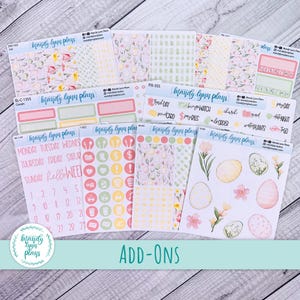 May include: A collection of planner stickers with floral and Easter egg designs. The stickers feature pastel colors, including pink, green, and yellow. Some stickers have text, such as "Hello Week" and daily labels. The stickers are labeled "Mandy Lynn Plans."
