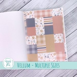 May include: Open notebook with graph paper pages and a decorative vellum cover. The cover features a patchwork design with floral, plaid, and striped patterns in shades of pink, beige, and blue. Text on the image reads "VELLUM - MULTIPLE SIZES."