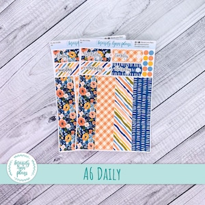 May include: A collection of A6 daily planner stickers featuring floral, checked, and striped designs in navy, peach, and yellow. The stickers include labels for each day of the week and decorative elements. The text "A6 DAILY" is at the bottom.