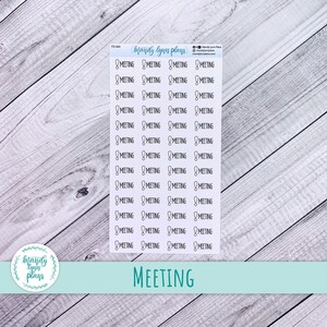 May include: A sheet of planner stickers with the word "MEETING" printed at the bottom. The stickers are white with black text and a meeting icon. The background is a light wood grain.