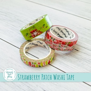 May include: Three rolls of washi tape featuring a strawberry patch design. The tape is green, pink and white with a pattern of strawberries, leaves and a basket of strawberries. The text on the tape reads "Mandy Lynn Plays".