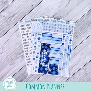 Puede incluir: Un conjunto de pegatinas para planificador con temática invernal. Las pegatinas presentan tonos de azul, copos de nieve y la palabra "Enero". Hay pegatinas de calendario, etiquetas y elementos decorativos. Las pegatinas están diseñadas para un planificador común.
