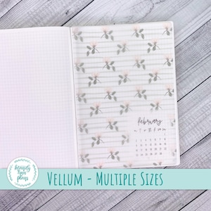 May include: Open notebook with a vellum overlay featuring a floral pattern and the February calendar. The vellum has a striped background with pink flowers. The text "VELLUM - MULTIPLE SIZES" is at the bottom.