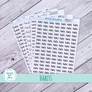May include: A stack of white sticker sheets with the word "habits" in a handwritten font. The stickers are arranged on a light wood-grain surface. The brand name "Mandy Lynn Plans" is visible.