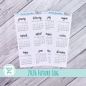 May include: A set of calendar stickers for 2026, featuring months from January to December. Each month is written in a stylish script font. The text "2026 FUTURE LOG" is at the bottom. The stickers are on a light wood grain surface.